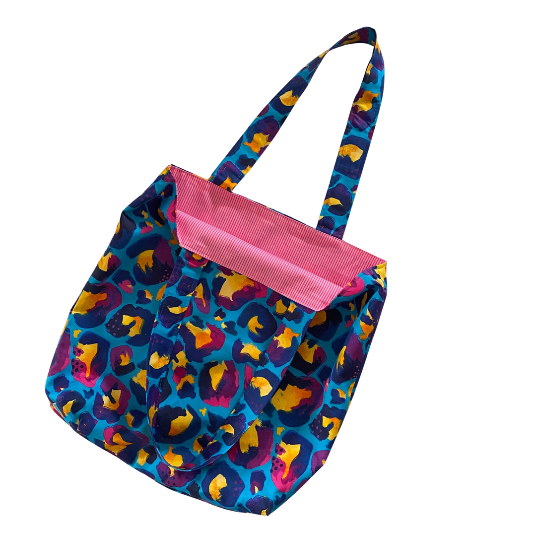 Colourful blue leopard patterned bag with pink interior on a white background.