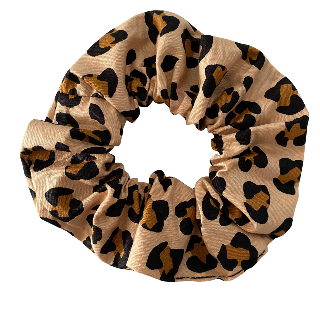 Leopard print scrunchie on a light brown background.