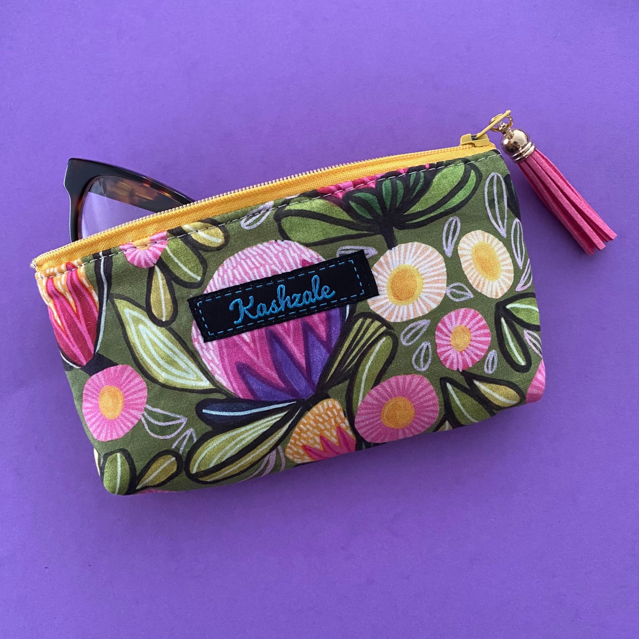 Protect your glasses with our padded, fully lined glasses case featuring colourful flowers on olive fabric by Kirsten Katz. Perfect pouch for eyewear and small essentials.