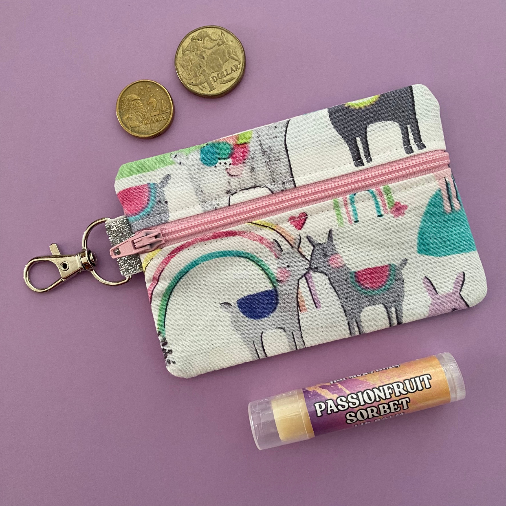 A clip coin purse with images of colourful llamas on a white fabric.