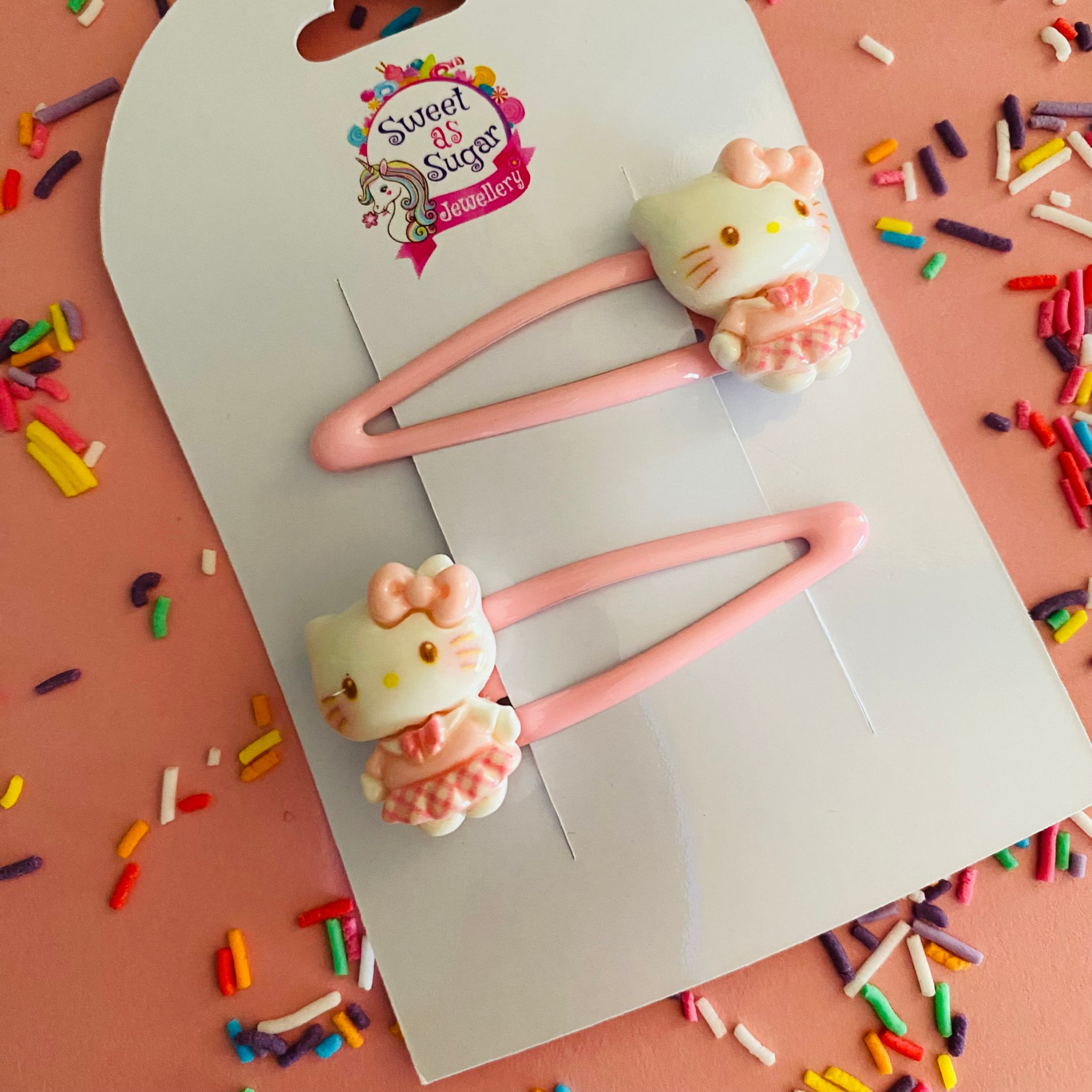 Two pink hair clips featuring a Hello Kitty charm.