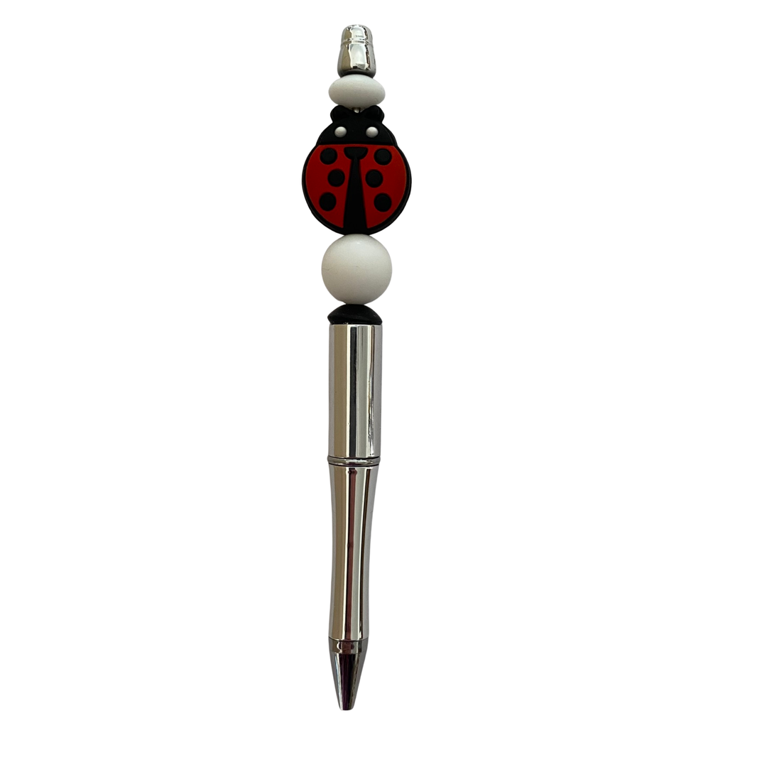 Pen with a ladybug silicone bead on top on a white background.