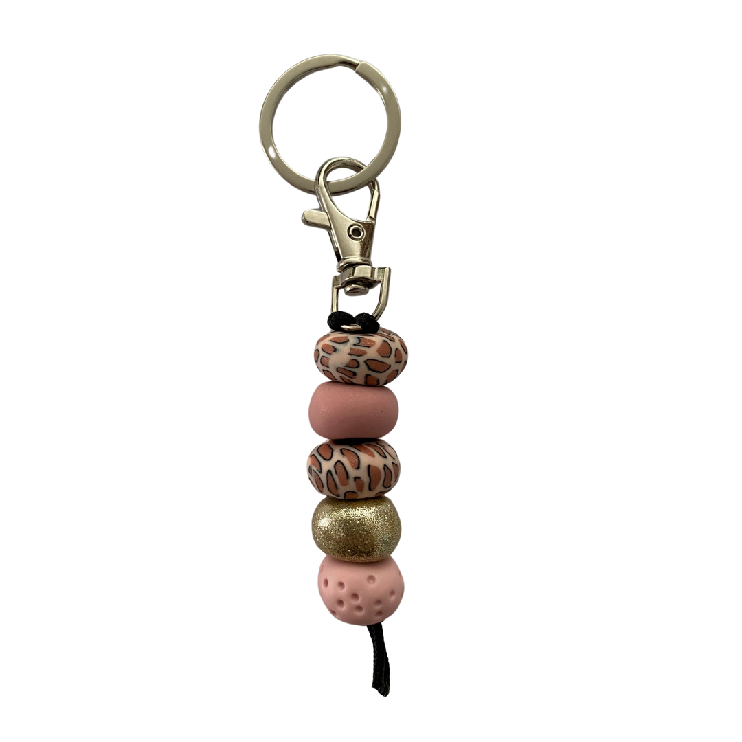 Handmade polymer clay keyring featuring five hand-rolled beads in a mix of dusty pinks, leopard print and gold glitter accents attached to a silver clasp.