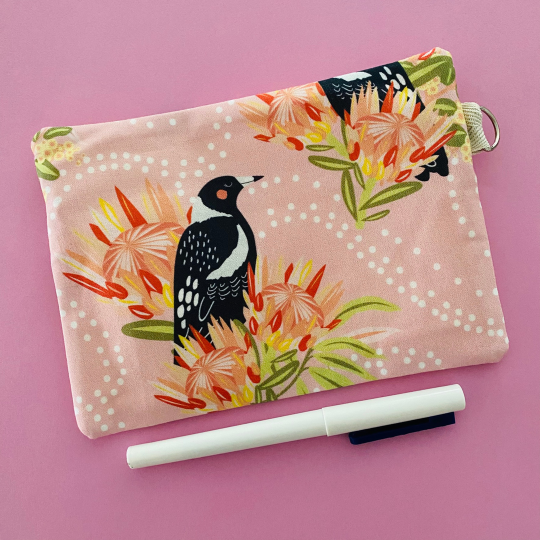 Fabric pouch showing reverse side with a Magpie and floral design on a light pink background.