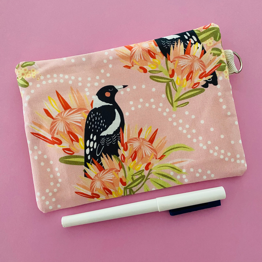 Fabric pouch showing reverse side with a Magpie and floral design on a light pink background.