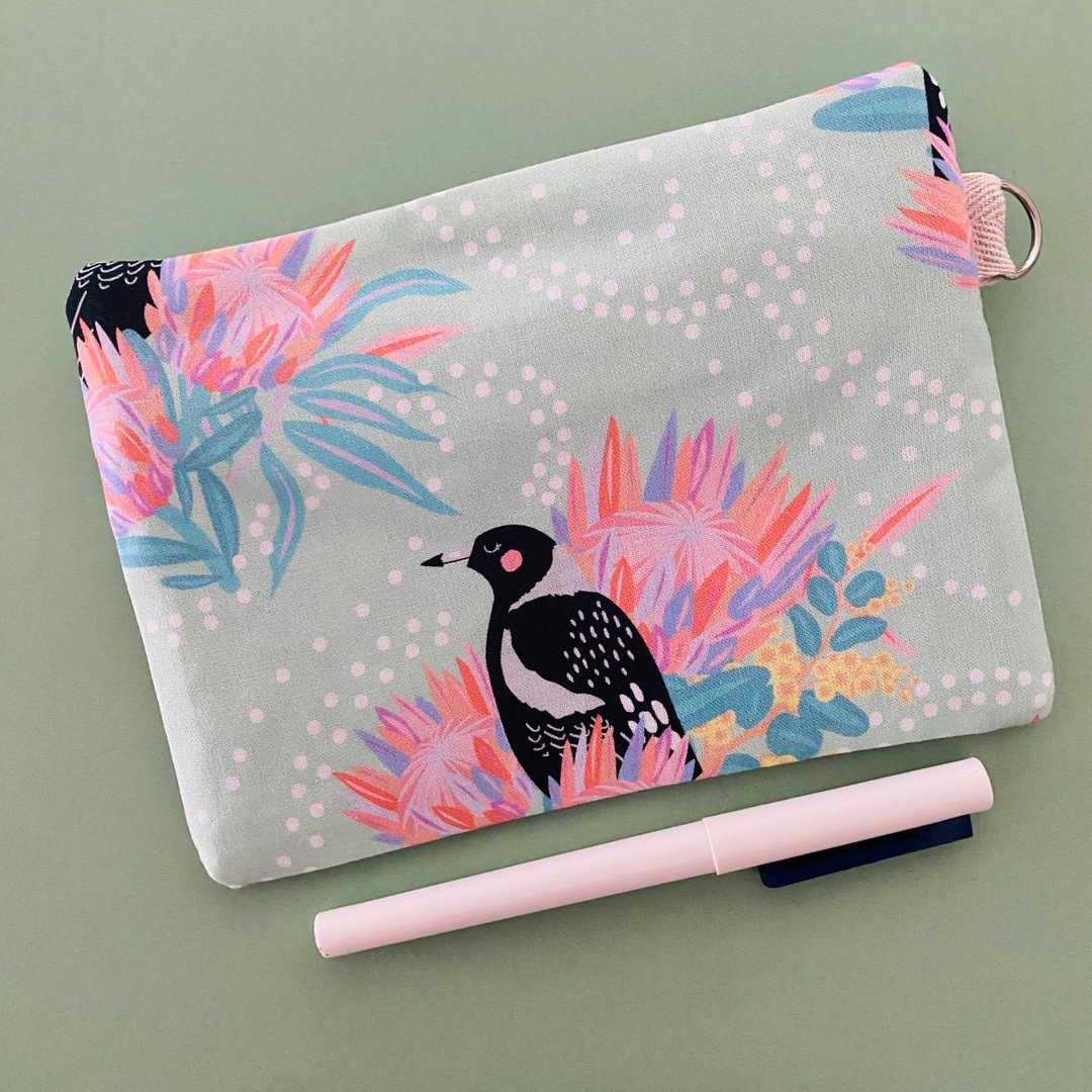 Fabric pouch showing reverse side with a Magpie and floral design on a light green background.