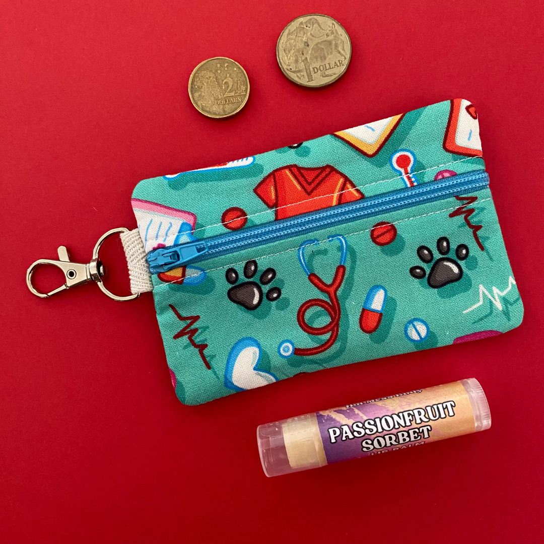 A small clip coin purse perfect for coins and small essentials decorated with playful illustrations of pills, scrubs, clipboards, stethoscopes, and paw prints, it’s ideal for medical students, nurses, doctors, and vet professionals.
