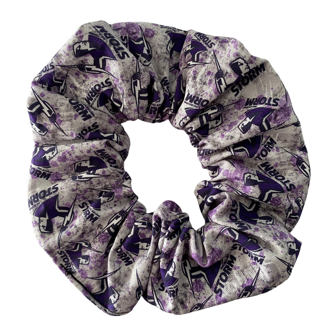 A scrunchie hair tie handmade with cotton woven fabric with images of the Melbourne Storm rugby league team.