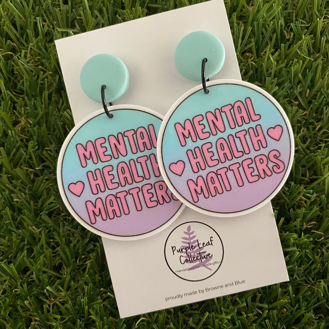 Stud dangle earrings with 'Mental Health Matters' printed across vibrant mint and pink circle discs.