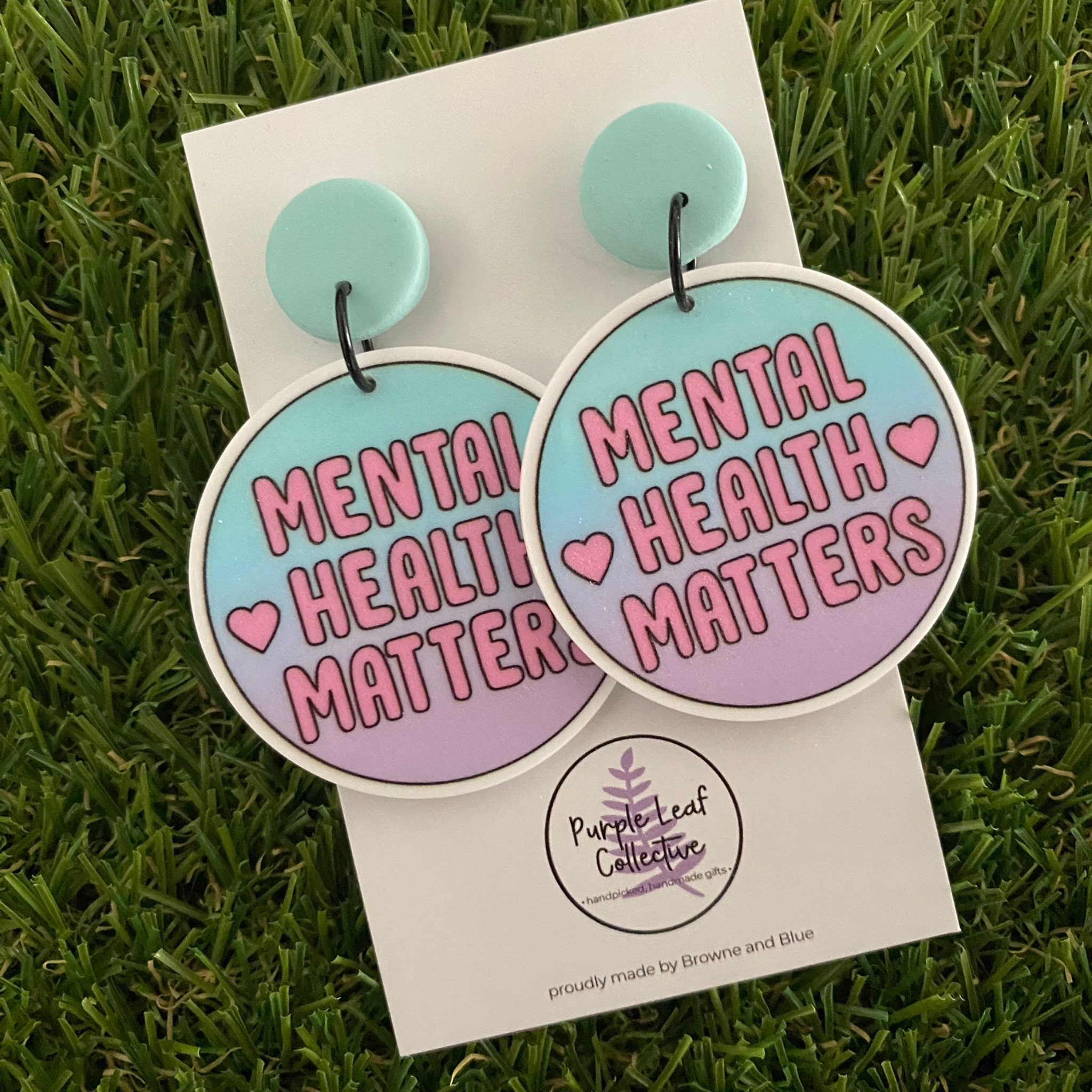 Stud dangle earrings with 'Mental Health Matters' printed across vibrant mint and pink circle discs.