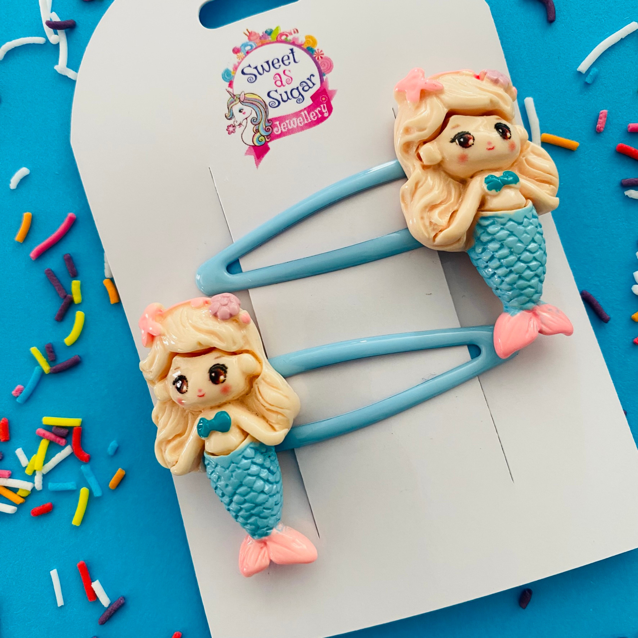 A pair of blue snap clips featuring a full length mermaid with a blue tail.