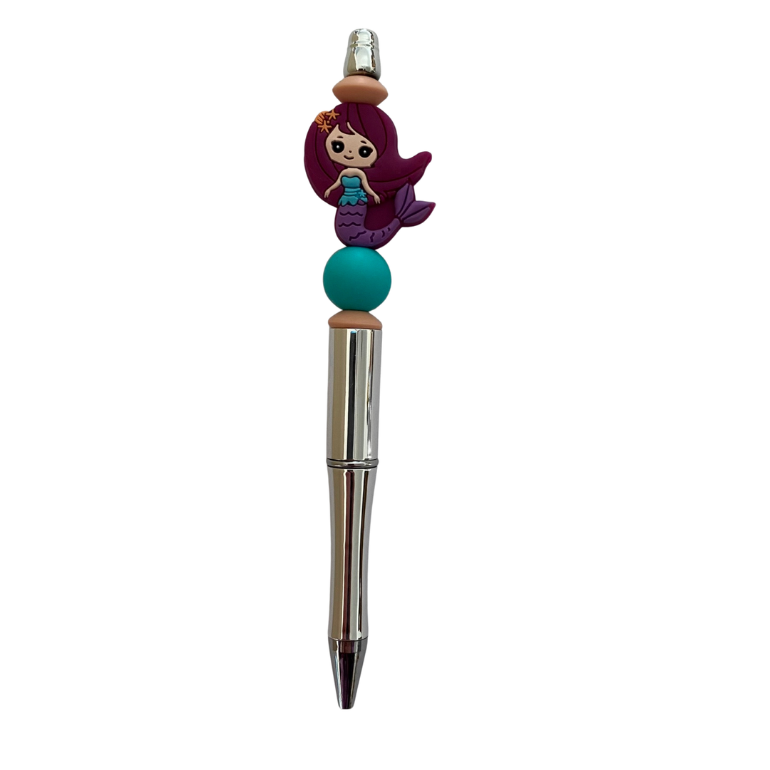 Pen with a mermaid purple silicone bead on top on a white background.