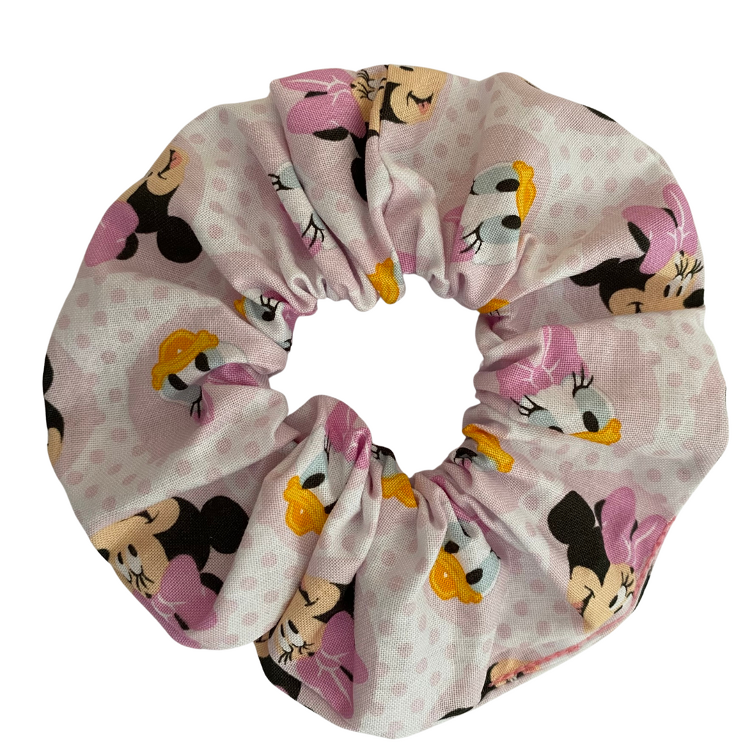 Minnie Mouse True Friends Scrunchie with adorable illustrations of Minnie Mouse and her bestie Daisy Duck on a soft pink fabric featuring durable braided elastic for secure styling.