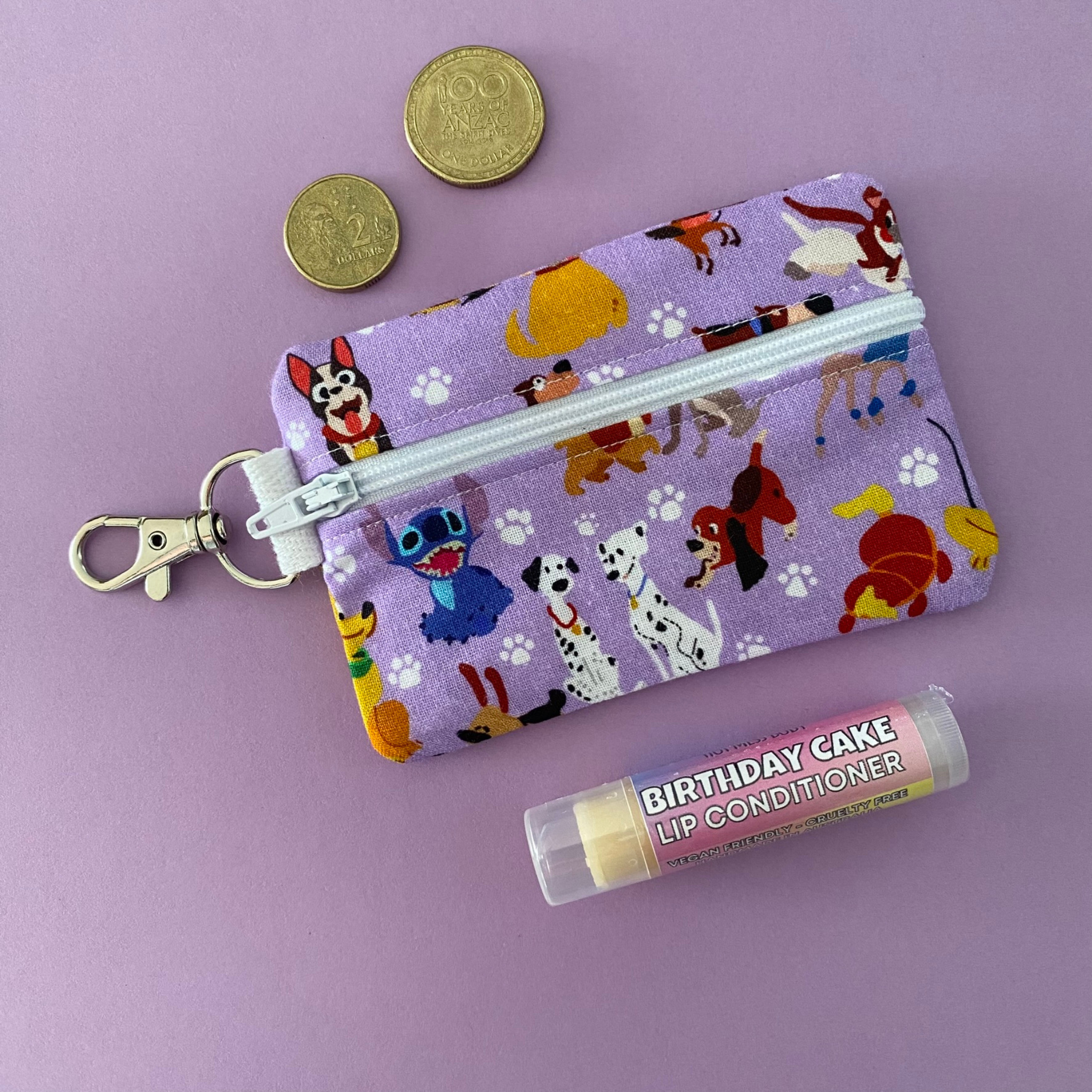 A small clip coin purse perfect for coins and small essentials featuring movie animals on a lilac fabric.