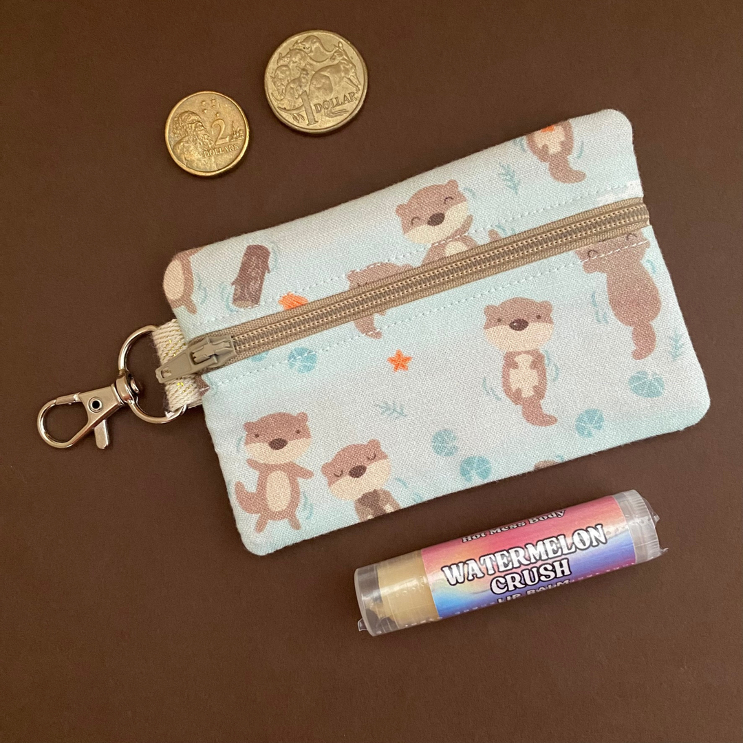 A clip coin purse with images of Otters on a light blue fabric.