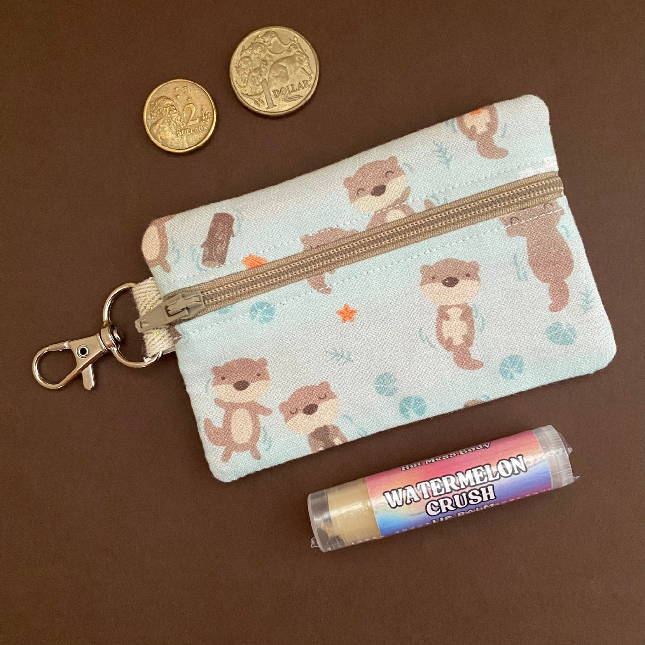 A clip coin purse with images of Otters on a light blue fabric.
