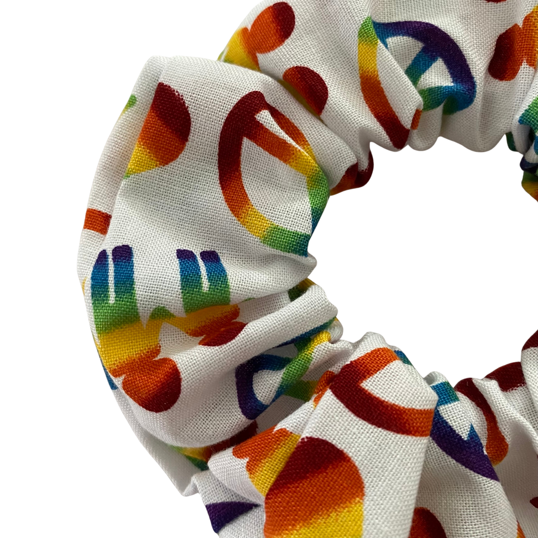 White scrunchie with rainbow peace sign pattern on a white background.