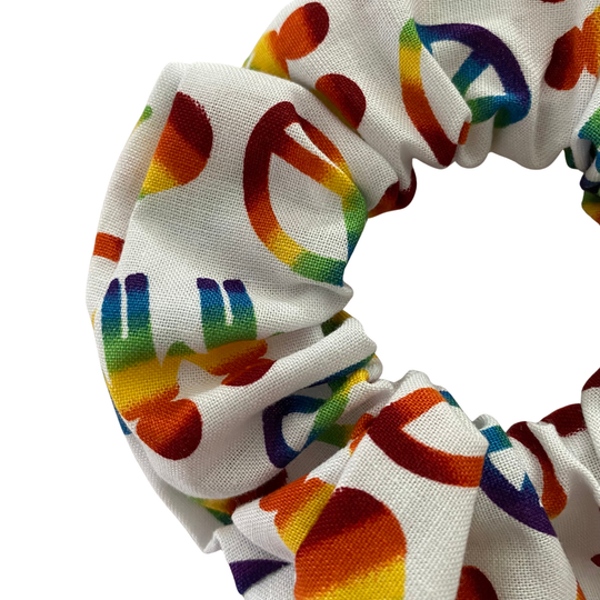 White scrunchie with rainbow peace sign pattern on a white background.