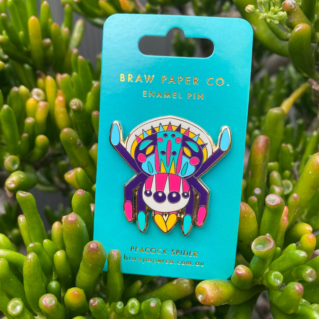 A picture of the Peacock Spider enamel pin on a backing card.