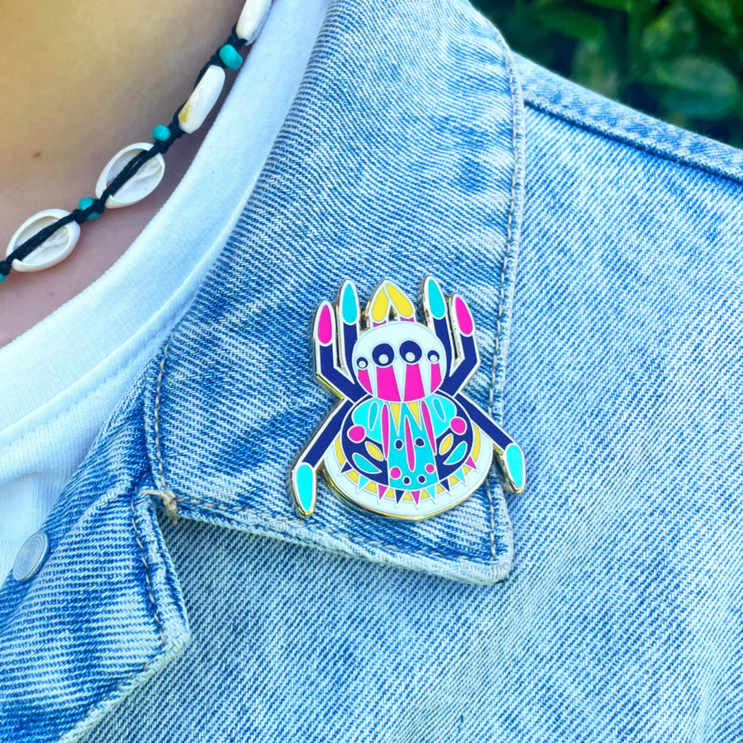 Colorful spider-shaped pin on a denim jacket.