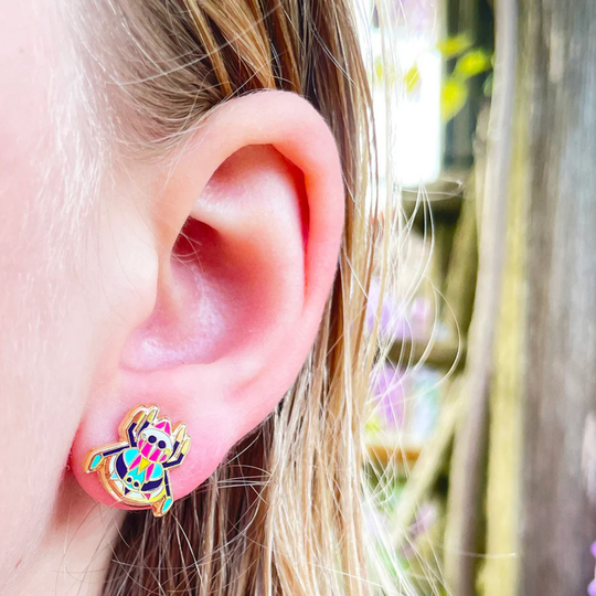Close-up of an ear wearing a Peacock Spider enamel stud earring.