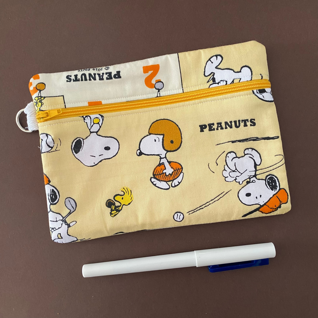 Zipper pouch with images of Snoopy playing sport on yellow fabric. Planner accessory for school or work. Perfect for small essentials.