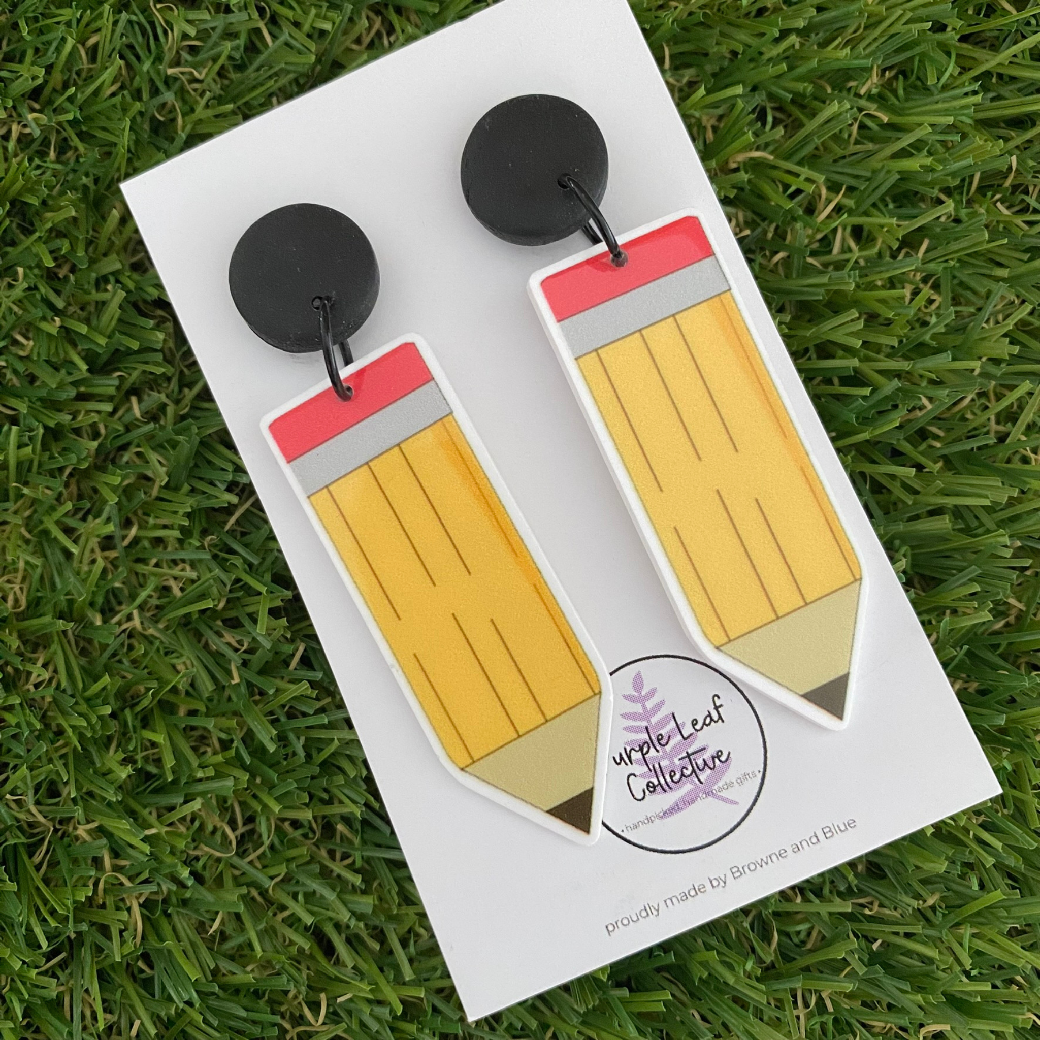 Pencil shaped dangle earrings set on black stud tops on white backing card.