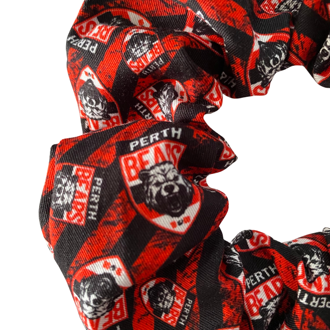 A close up view of a black and red scrunchie featuring the team logo for Perth Bears.