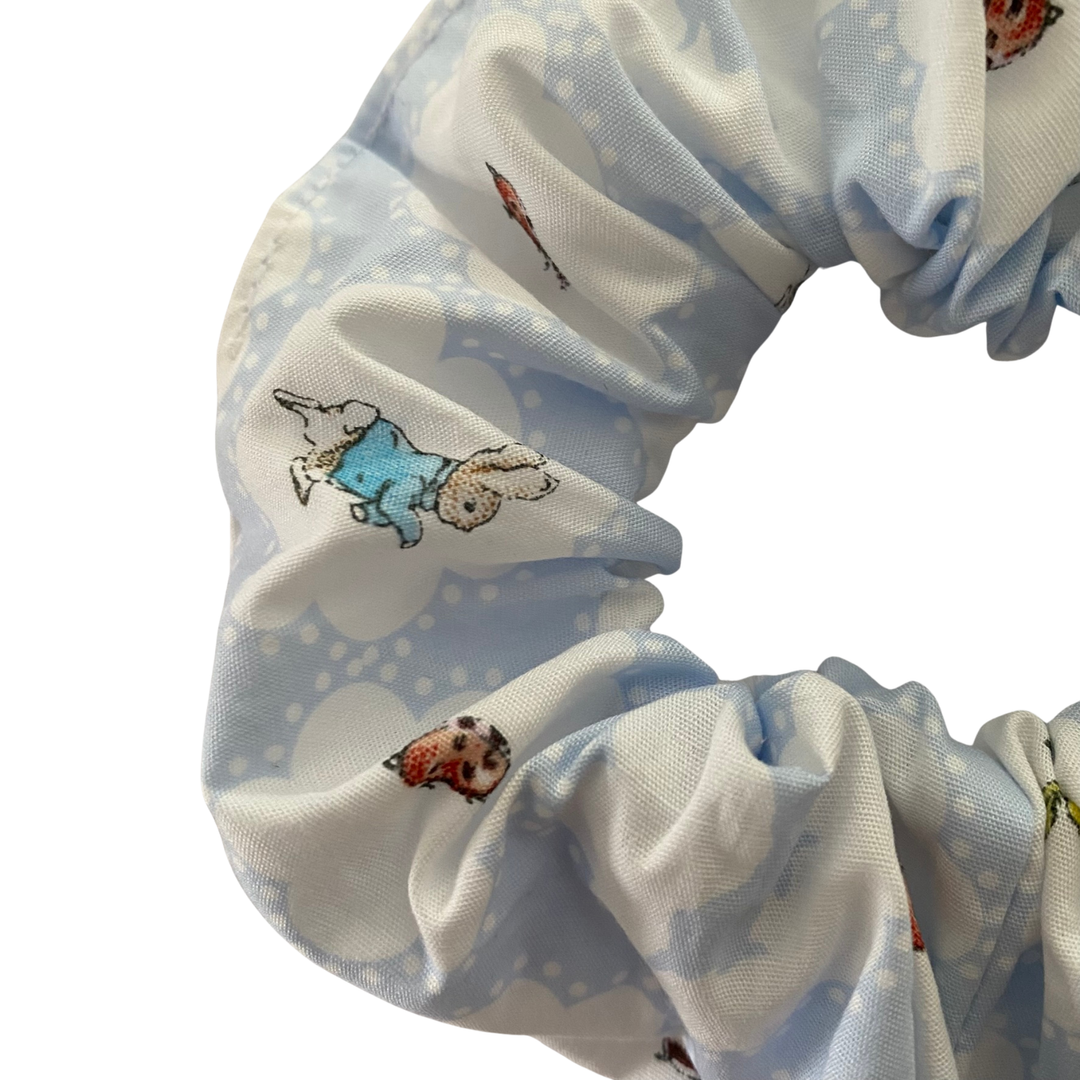 Close-up view of the Peter Rabbit scrunchie, highlighting the detailed character illustrations on soft woven cotton.