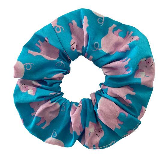 Blue scrunchie with pink pig pattern on a white background.