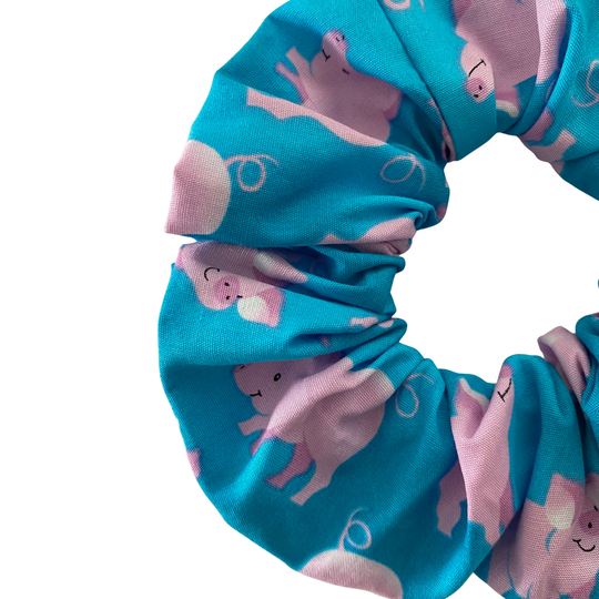 Pink pig pattern scrunchie on blue fabric.