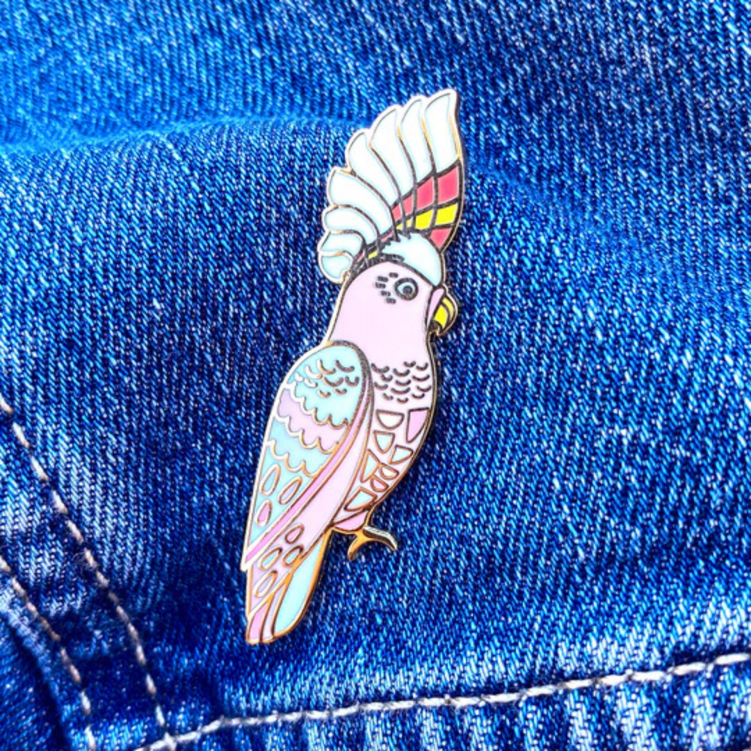 The Pink Cockatoo Enamel Pin pinned on a denim jacket.
