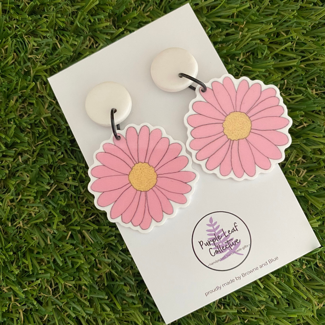 Pink daisy dangle earrings featuring pink petal flowers with a lemon centre set on white clay tops.