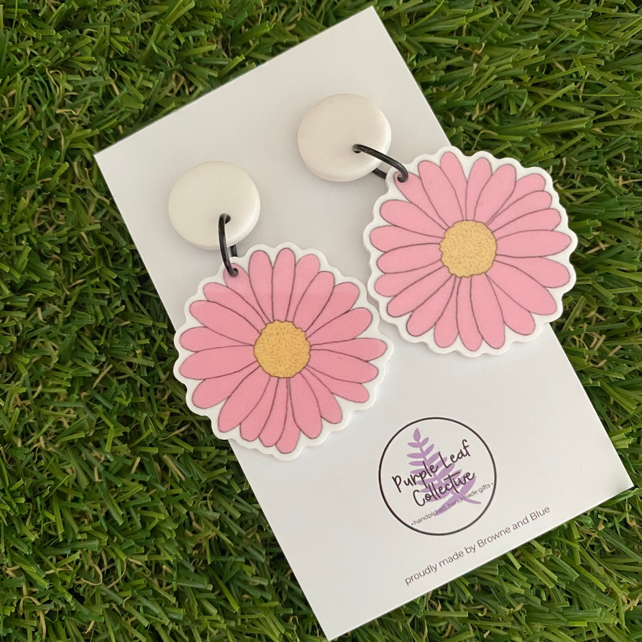 Pink daisy dangle earrings featuring pink petal flowers with a lemon centre set on white clay tops.