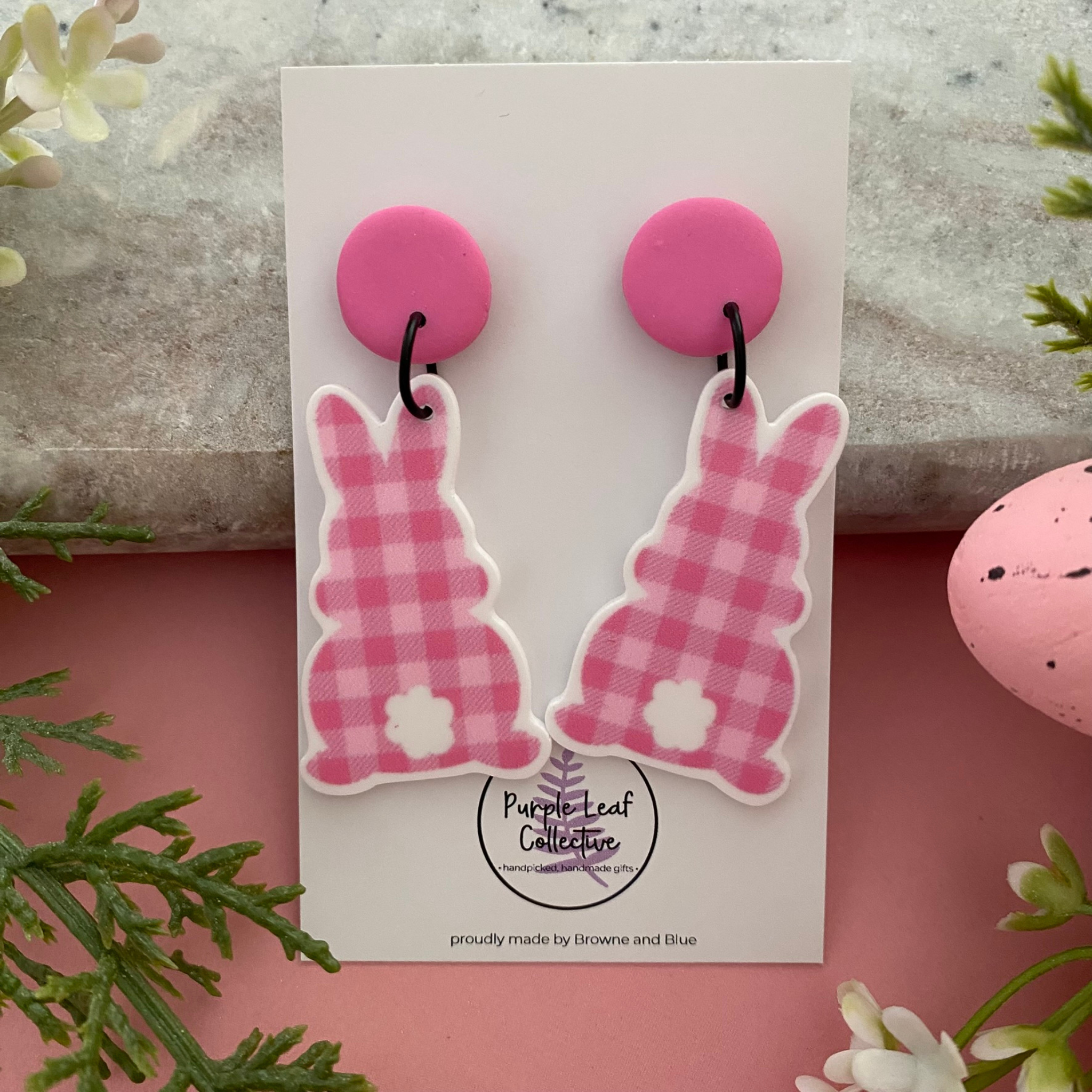 Handmade pink gingham pattern bunny earrings styled with Easter decorations and spring flowers.