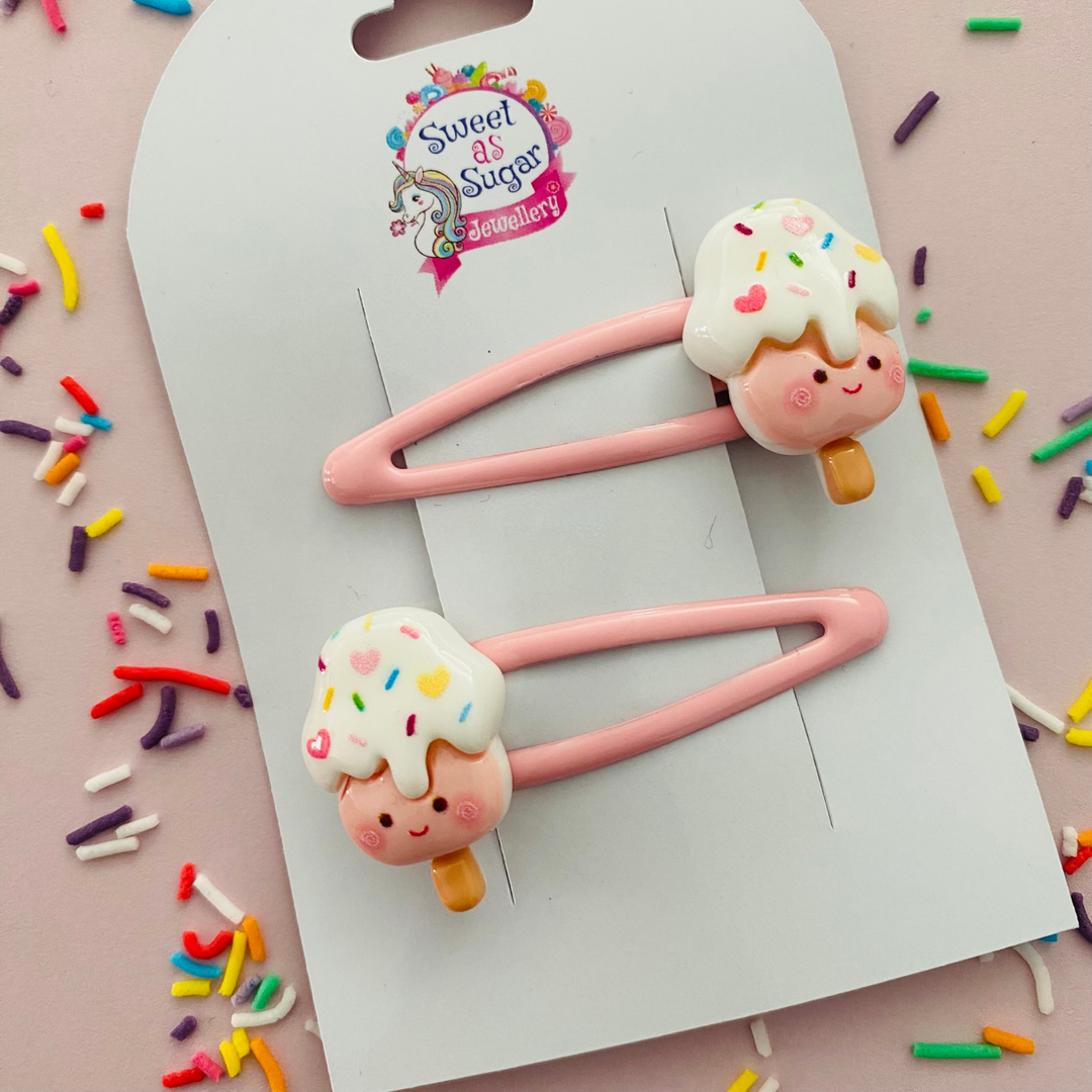 A pair of pink snap hair clips with a pink soft serve ice cream cone charm.