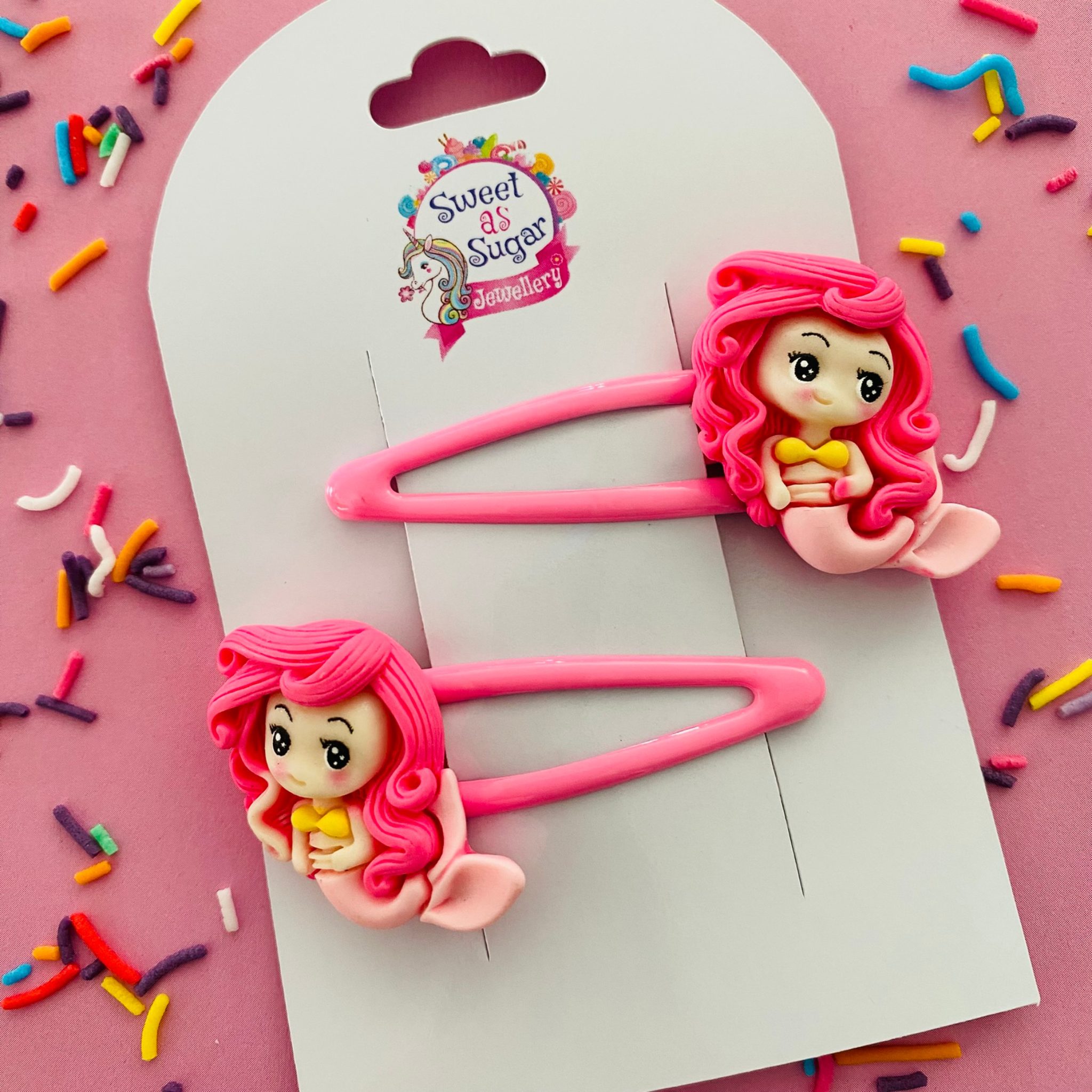 A pair of pink snap clips  featuring a full length pink mermaid with pink hair and a pink tail.