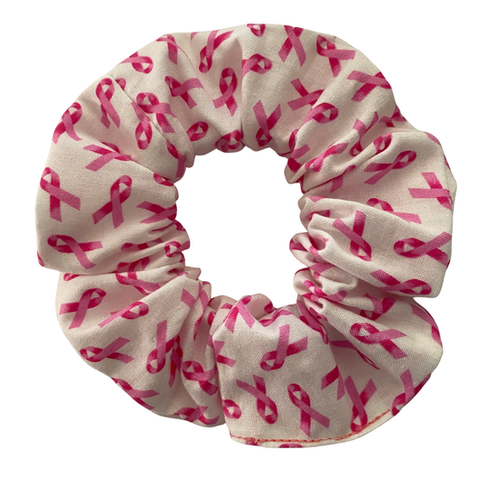 A white scrunchie with the iconic pink ribbon symbol in a repeat print.