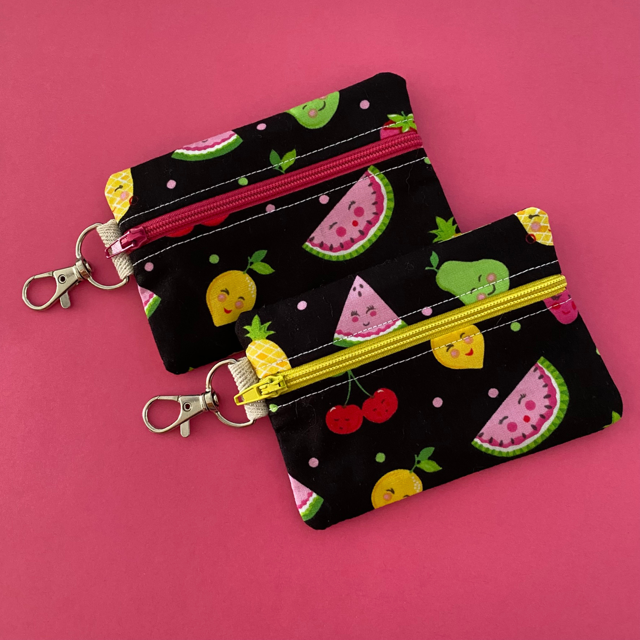 A clip coin purse with images of smiling fruit on black fabric.