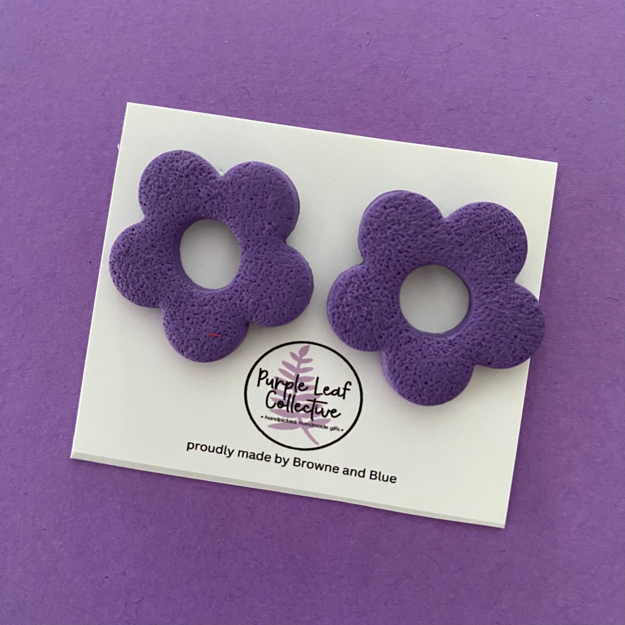 Drop stud earrings with five purple polymer clay flower petals, set on surgical steel posts for comfort and durability.