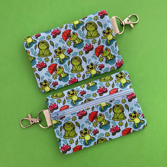 Reverse view of a mini pouch with images of frogs holding umbrellas and lily pads on a crisp blue fabric.