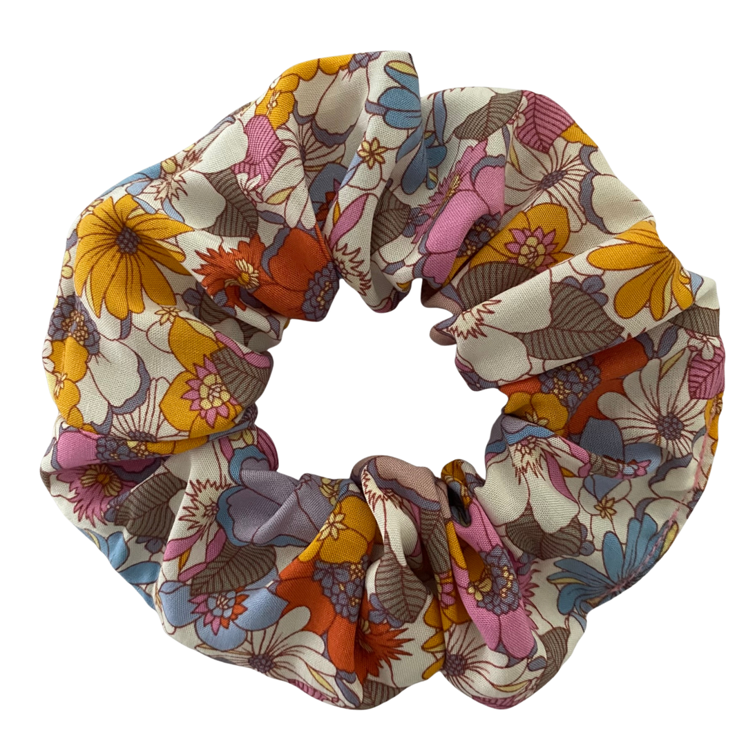 A scrunchie featuring multicoloured retro floral pattern with pink, lilac, blue, orange and yellow blossoms.