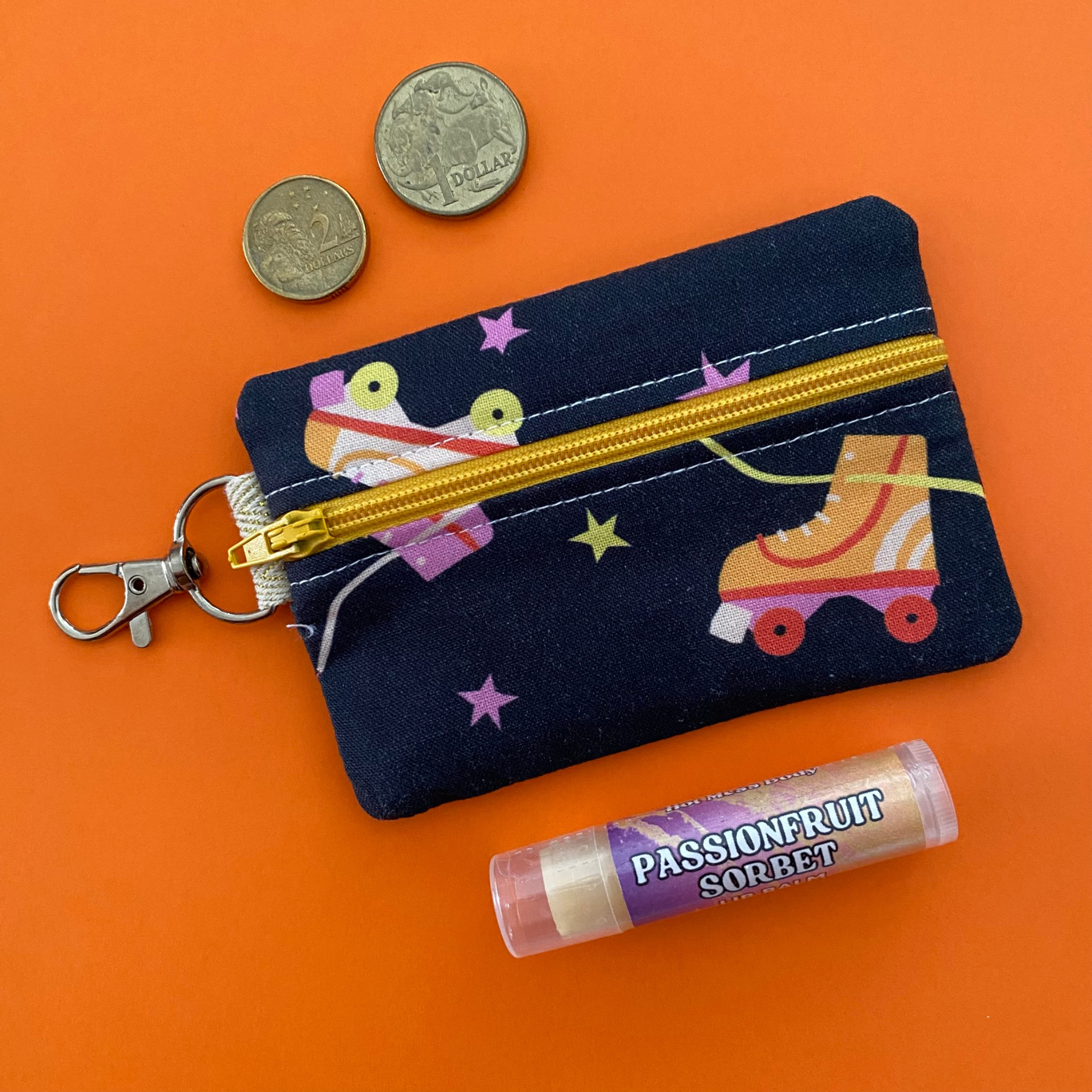 A clip coin purse with images of roller skates on a black fabric.