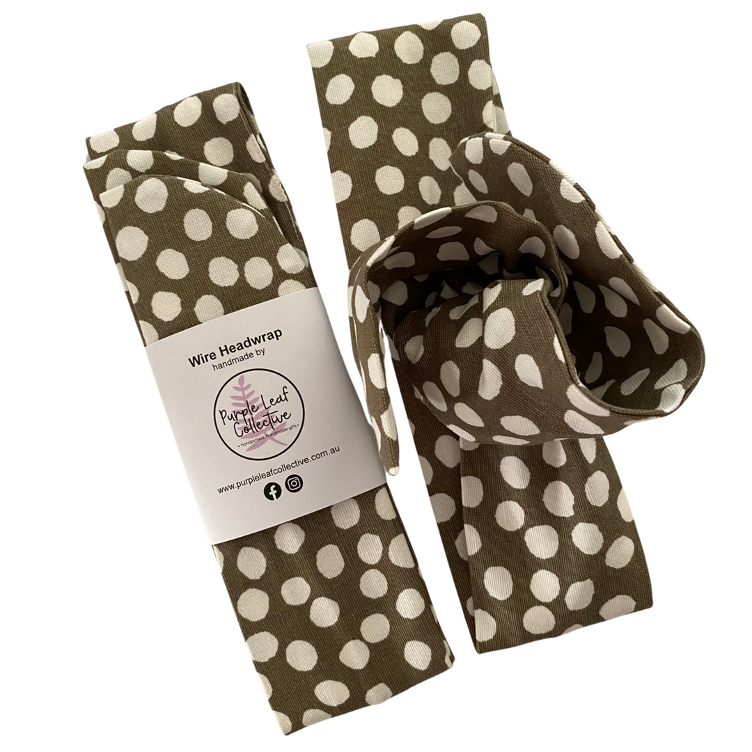 Sage green headwrap with white polka dots on a white background, featuring the Purple Leaf Collective branding.