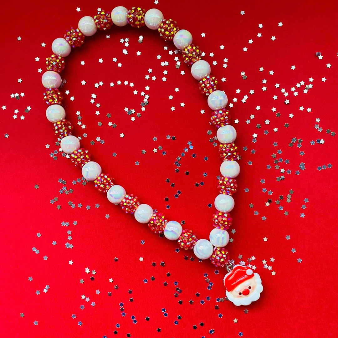 A beaded Christmas necklace featuring white iridescent beads, red beads covered in small gold rhinestones, and a Santa Claus face charm.