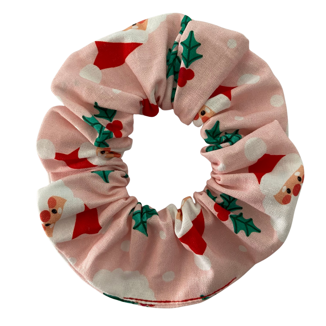 Pink scrunchie with Santa Claus and holly design on a white background.