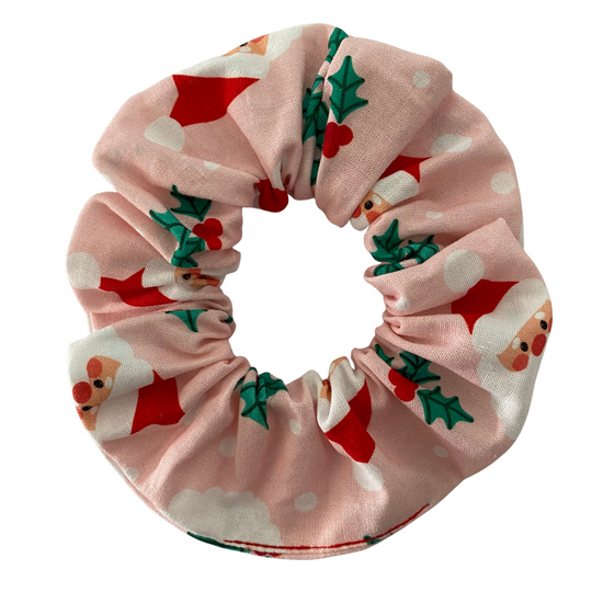 A pink fabric scrunchie featuring images of Santa Claus face.