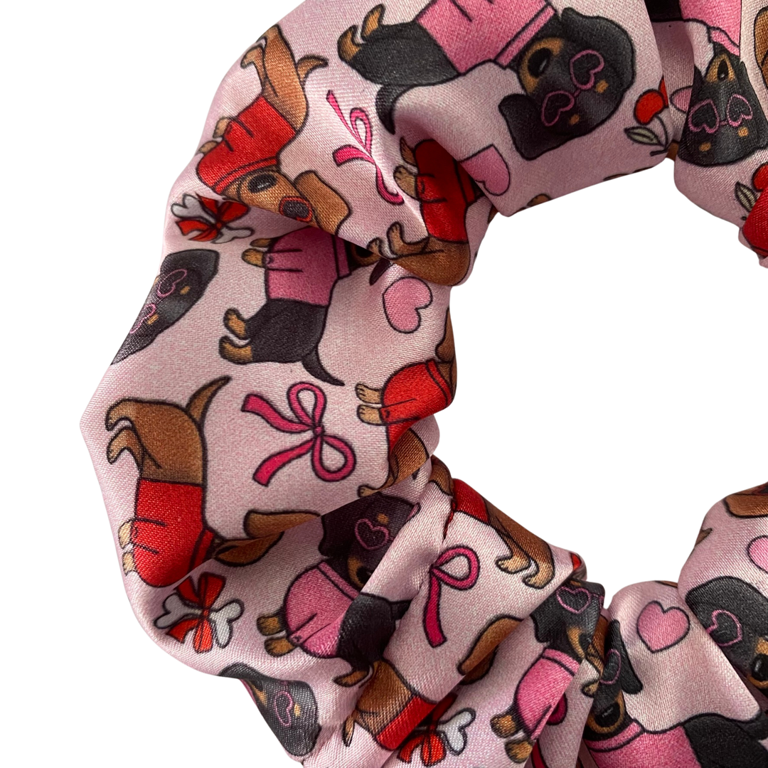Pink scrunchie with dog pattern on a white background.