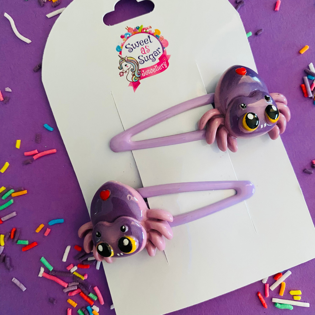 Spider hair clips feature a creepy eight-legged purple spider with bulging eyes, set on a lilac hair clip.