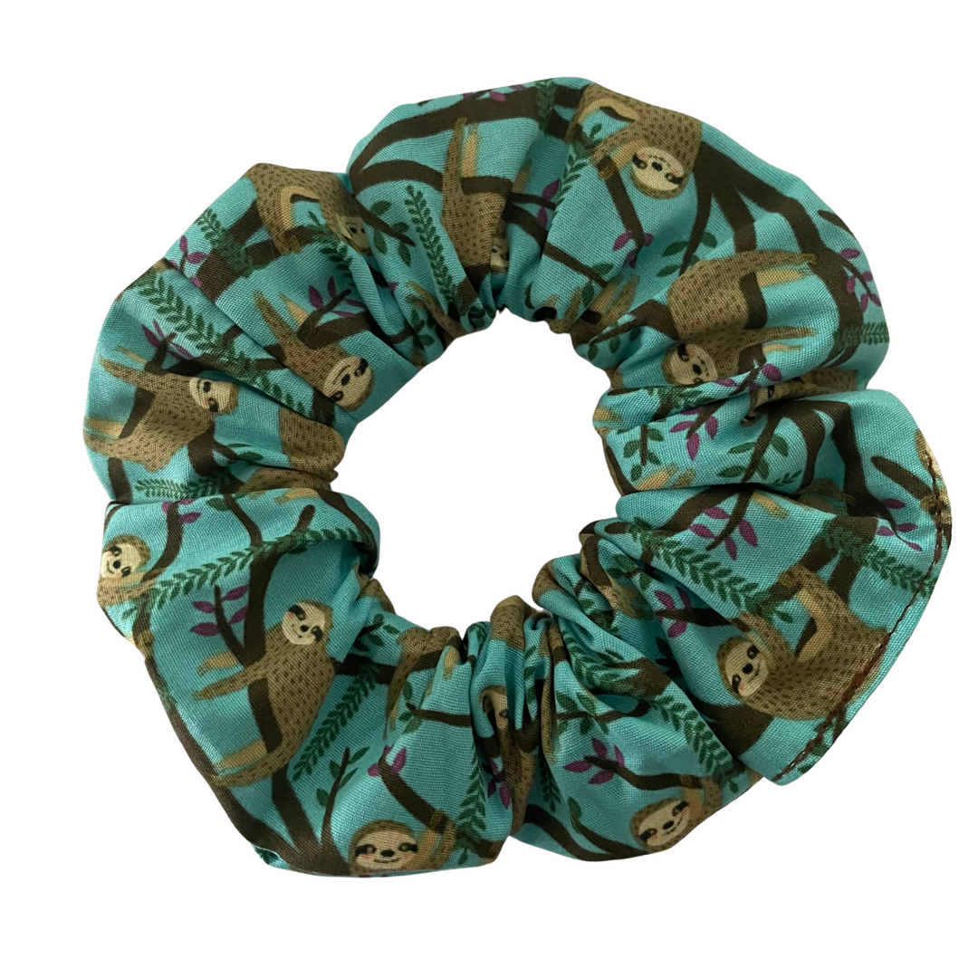 A teal fabric scrunchie with images of brown Sloths hanging off trees.